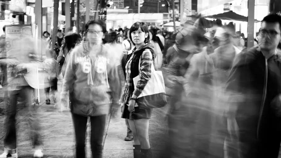 People walking along a sidewalk. Some are smiling. The frame includes children.