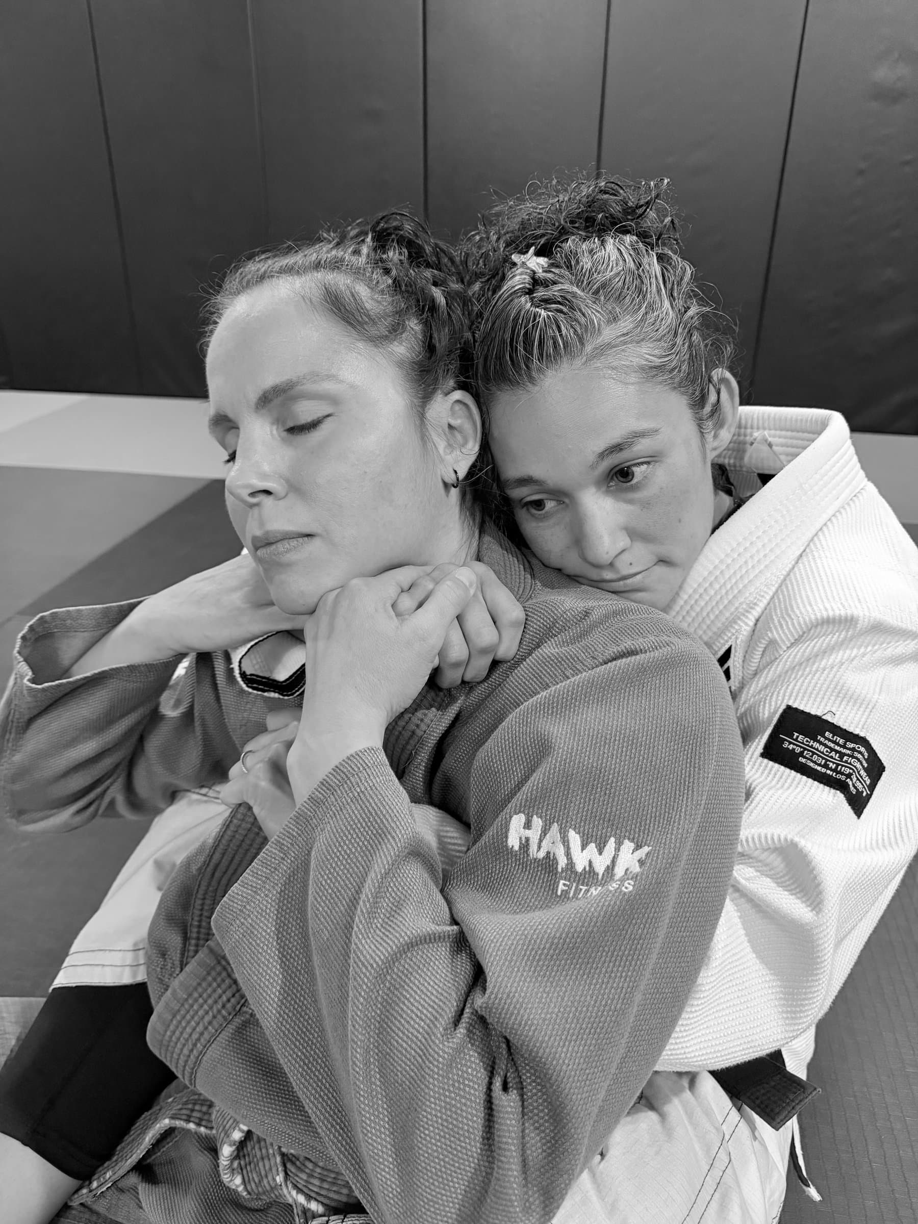 Two women in gis during a grappling hold in training.
